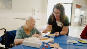 A woman is painting as an activity at a skilled nursing facility