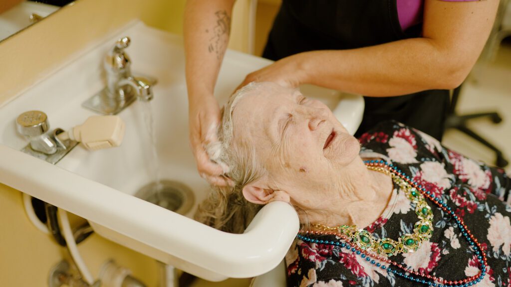 A woman is getting her hair washed in a salon at a skilled nursing facility