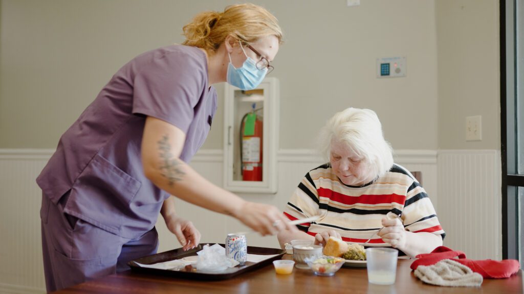A woman is getting her lunch at a skilled nursing facility