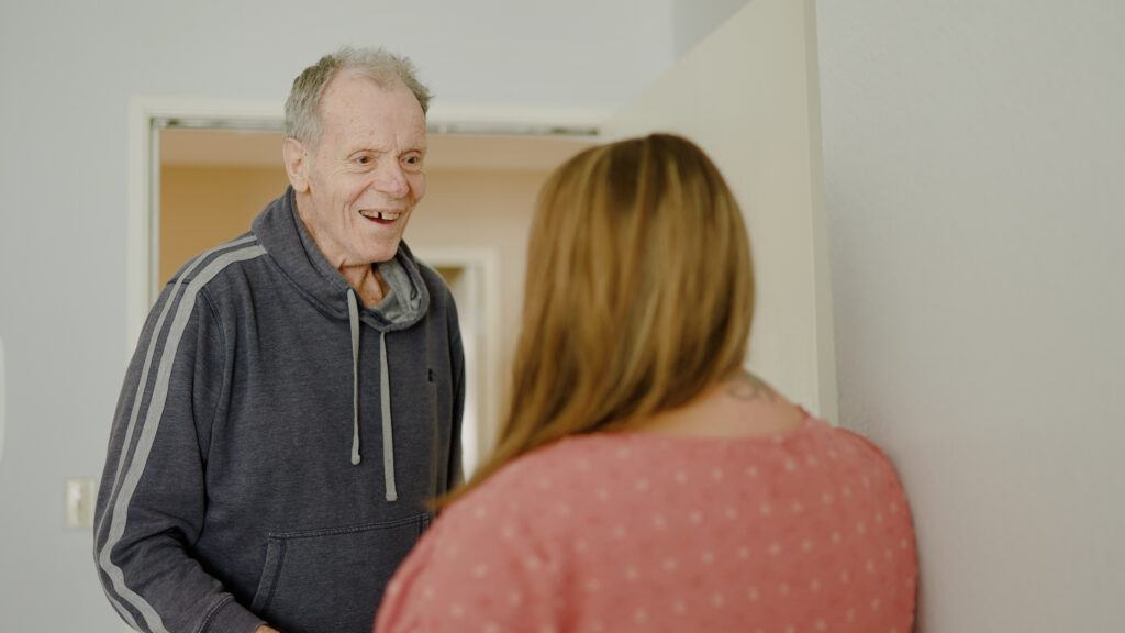 A man smiles at a nurse while talking in the hallway