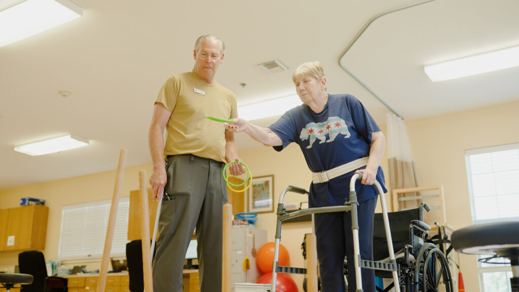 A woman doing physical therapy with a nurse at a skilled nursing facility